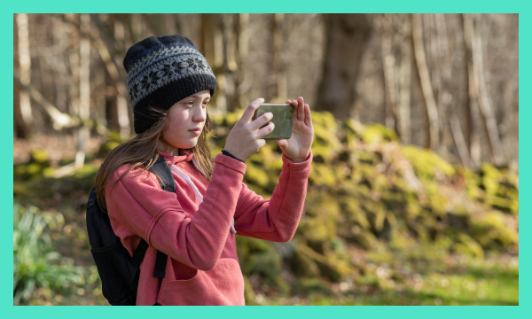 Young person in forest taking pictures with phone