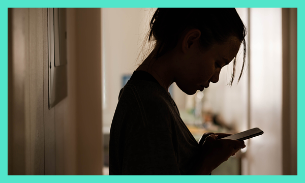 Silhouette of young person using phone